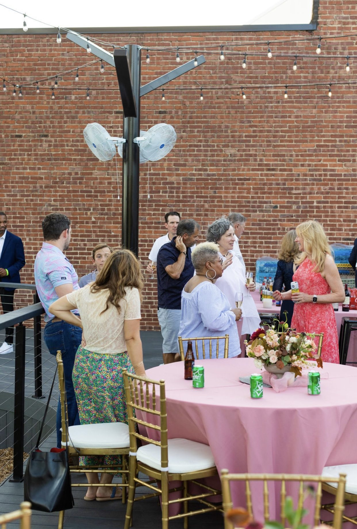 Pink linen tables and florals on the deck against exposed brick